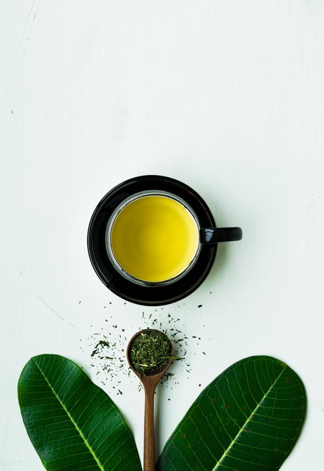 Green tea leaves and a freshly brewed cup of green tea