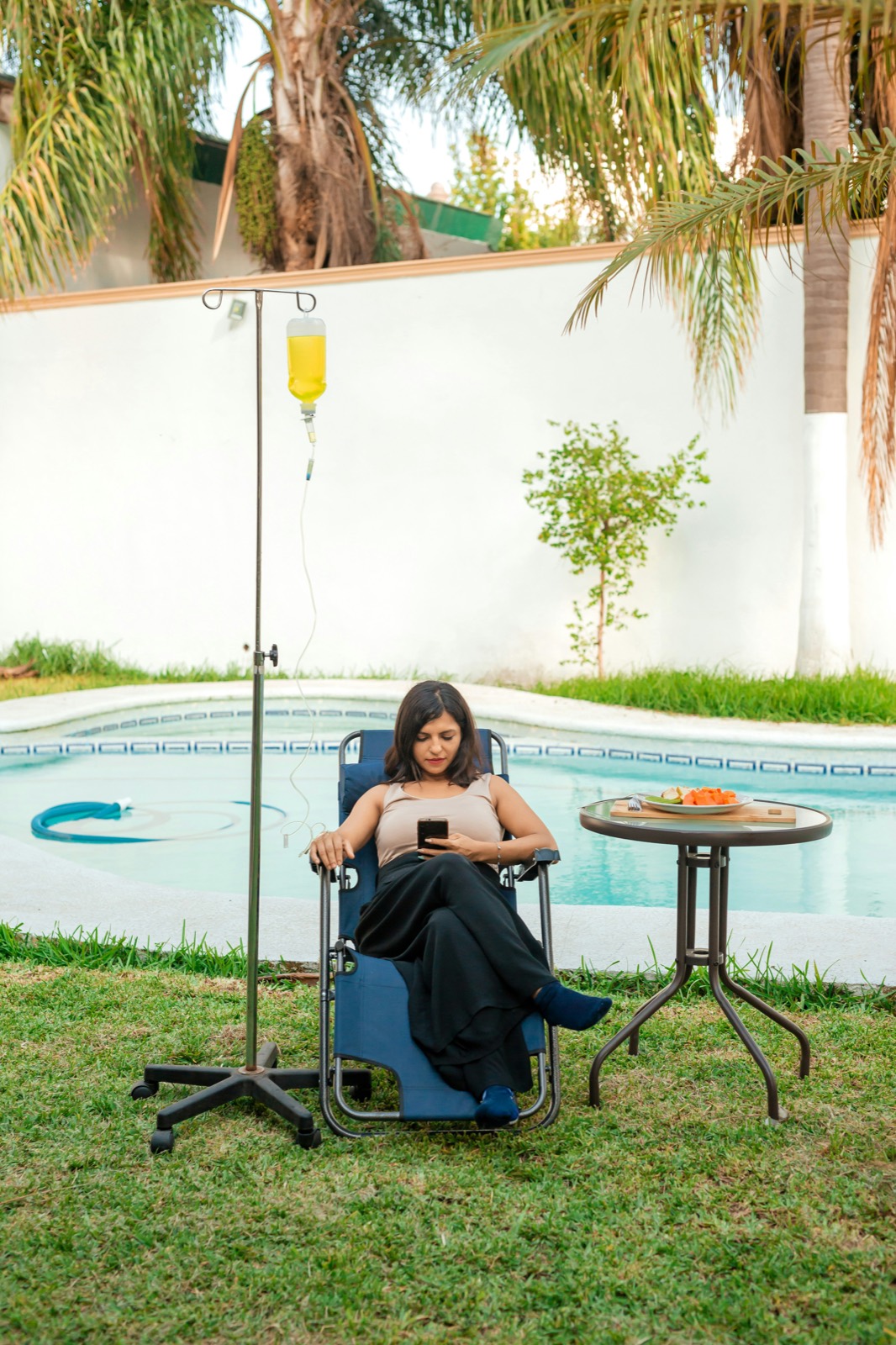 A woman relaxes poolside with an IV drip during an NAD+ infusion